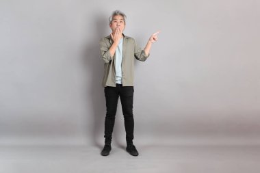 Gri arka planda duran 40 'lı yılların Asyalı, şık, sıradan elbiseli adamı.. 