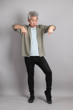 Gri arka planda duran 40 'lı yılların Asyalı, şık, sıradan elbiseli adamı.. 