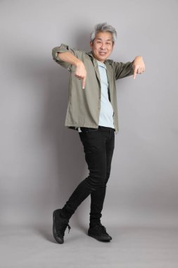 Gri arka planda duran 40 'lı yılların Asyalı, şık, sıradan elbiseli adamı.. 