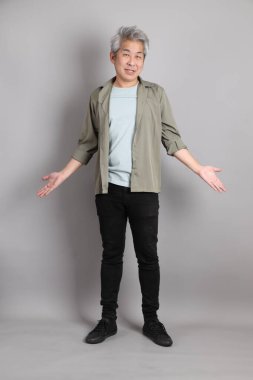 Gri arka planda duran 40 'lı yılların Asyalı, şık, sıradan elbiseli adamı.. 