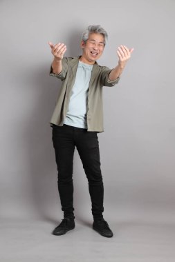 Gri arka planda duran 40 'lı yılların Asyalı, şık, sıradan elbiseli adamı.. 