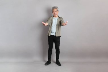 Gri arka planda duran 40 'lı yılların Asyalı, şık, sıradan elbiseli adamı.. 