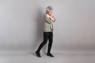 Gri arka planda duran 40 'lı yılların Asyalı, şık, sıradan elbiseli adamı.. 