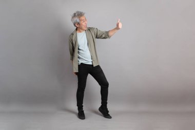 Gri arka planda duran 40 'lı yılların Asyalı, şık, sıradan elbiseli adamı.. 