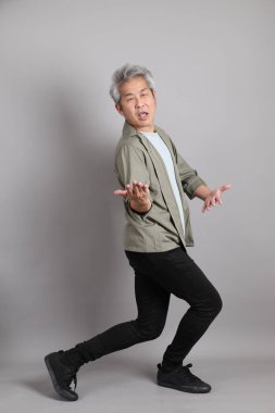 Gri arka planda duran 40 'lı yılların Asyalı, şık, sıradan elbiseli adamı.. 