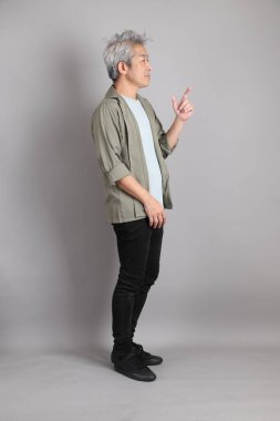 Gri arka planda duran 40 'lı yılların Asyalı, şık, sıradan elbiseli adamı.. 