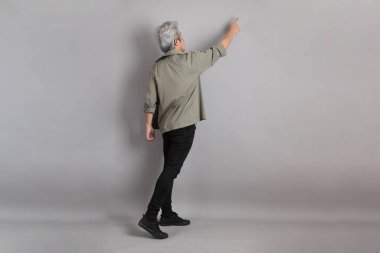 Gri arka planda duran 40 'lı yılların Asyalı, şık, sıradan elbiseli adamı.. 