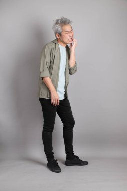 Gri arka planda duran 40 'lı yılların Asyalı, şık, sıradan elbiseli adamı.. 