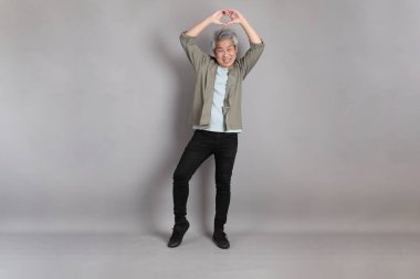 Gri arka planda duran 40 'lı yılların Asyalı, şık, sıradan elbiseli adamı.. 