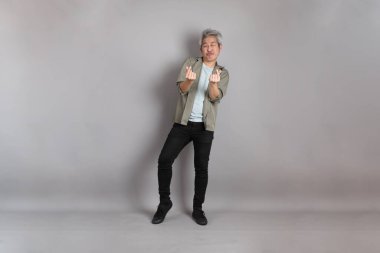 Gri arka planda duran 40 'lı yılların Asyalı, şık, sıradan elbiseli adamı.. 