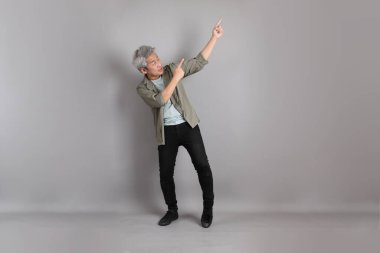 Gri arka planda duran 40 'lı yılların Asyalı, şık, sıradan elbiseli adamı.. 