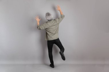 Gri arka planda duran 40 'lı yılların Asyalı, şık, sıradan elbiseli adamı.. 