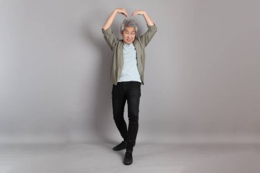 Gri arka planda duran 40 'lı yılların Asyalı, şık, sıradan elbiseli adamı.. 