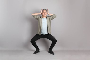 Gri arka planda duran 40 'lı yılların Asyalı, şık, sıradan elbiseli adamı.. 