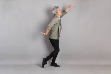 Gri arka planda duran 40 'lı yılların Asyalı, şık, sıradan elbiseli adamı.. 