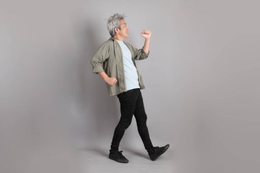 Gri arka planda duran 40 'lı yılların Asyalı, şık, sıradan elbiseli adamı.. 