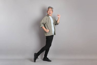 Gri arka planda duran 40 'lı yılların Asyalı, şık, sıradan elbiseli adamı.. 