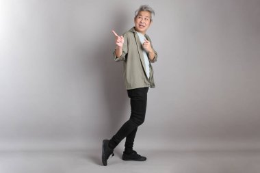 Gri arka planda duran 40 'lı yılların Asyalı, şık, sıradan elbiseli adamı.. 