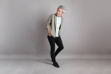 Gri arka planda duran 40 'lı yılların Asyalı, şık, sıradan elbiseli adamı.. 