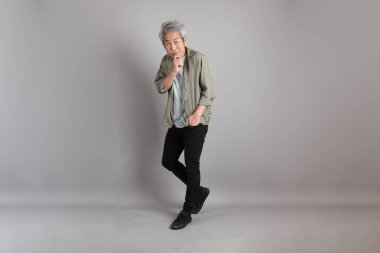 Gri arka planda duran 40 'lı yılların Asyalı, şık, sıradan elbiseli adamı.. 