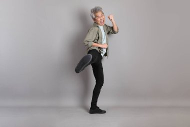 Gri arka planda duran 40 'lı yılların Asyalı, şık, sıradan elbiseli adamı.. 