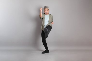 Gri arka planda duran 40 'lı yılların Asyalı, şık, sıradan elbiseli adamı.. 