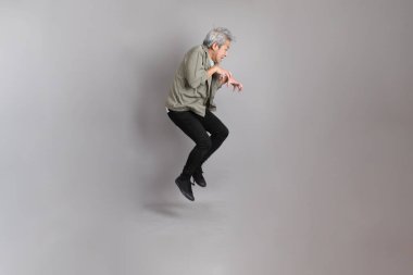 Gri arka planda duran 40 'lı yılların Asyalı, şık, sıradan elbiseli adamı.. 