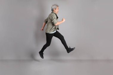 Gri arka planda duran 40 'lı yılların Asyalı, şık, sıradan elbiseli adamı.. 