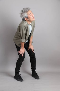 Gri arka planda duran 40 'lı yılların Asyalı, şık, sıradan elbiseli adamı.. 