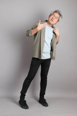 Gri arka planda duran 40 'lı yılların Asyalı, şık, sıradan elbiseli adamı.. 