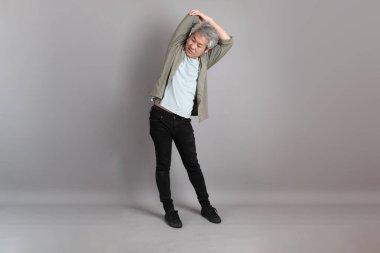 Gri arka planda duran 40 'lı yılların Asyalı, şık, sıradan elbiseli adamı.. 