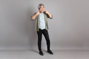 Gri arka planda duran 40 'lı yılların Asyalı, şık, sıradan elbiseli adamı.. 