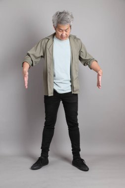 Gri arka planda duran 40 'lı yılların Asyalı, şık, sıradan elbiseli adamı.. 