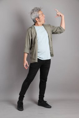 Gri arka planda duran 40 'lı yılların Asyalı, şık, sıradan elbiseli adamı.. 