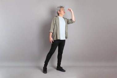 Gri arka planda duran 40 'lı yılların Asyalı, şık, sıradan elbiseli adamı.. 