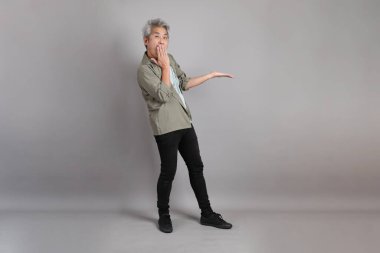 Gri arka planda duran 40 'lı yılların Asyalı, şık, sıradan elbiseli adamı.. 