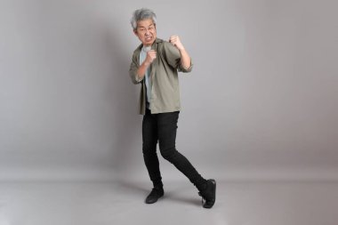 Gri arka planda duran 40 'lı yılların Asyalı, şık, sıradan elbiseli adamı.. 