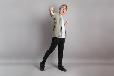 Gri arka planda duran 40 'lı yılların Asyalı, şık, sıradan elbiseli adamı.. 