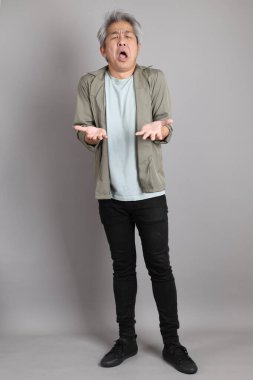 Gri arka planda duran 40 'lı yılların Asyalı, şık, sıradan elbiseli adamı.. 