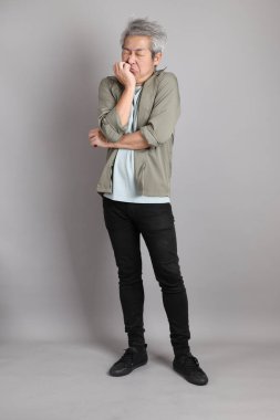 Gri arka planda duran 40 'lı yılların Asyalı, şık, sıradan elbiseli adamı.. 