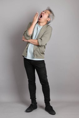 Gri arka planda duran 40 'lı yılların Asyalı, şık, sıradan elbiseli adamı.. 