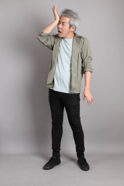 Gri arka planda duran 40 'lı yılların Asyalı, şık, sıradan elbiseli adamı.. 