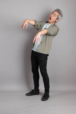 Gri arka planda duran 40 'lı yılların Asyalı, şık, sıradan elbiseli adamı.. 