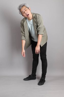 Gri arka planda duran 40 'lı yılların Asyalı, şık, sıradan elbiseli adamı.. 