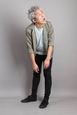 Gri arka planda duran 40 'lı yılların Asyalı, şık, sıradan elbiseli adamı.. 