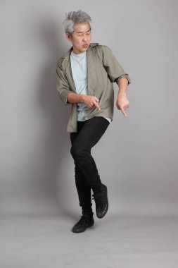 Gri arka planda duran 40 'lı yılların Asyalı, şık, sıradan elbiseli adamı.. 