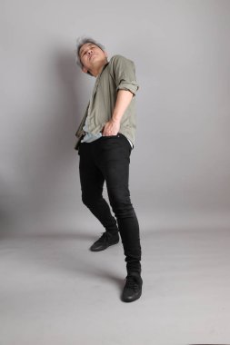 Gri arka planda duran 40 'lı yılların Asyalı, şık, sıradan elbiseli adamı.. 