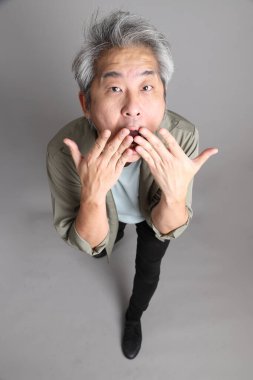 Gri arka planda duran 40 'lı yılların Asyalı, şık, sıradan elbiseli adamı.. 