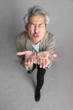 Gri arka planda duran 40 'lı yılların Asyalı, şık, sıradan elbiseli adamı.. 