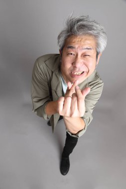 Gri arka planda duran 40 'lı yılların Asyalı, şık, sıradan elbiseli adamı.. 